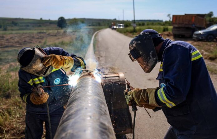 Boru kaynakçısı, açık alanda kaynak yaparken güvenlik önlemleri alıyor.